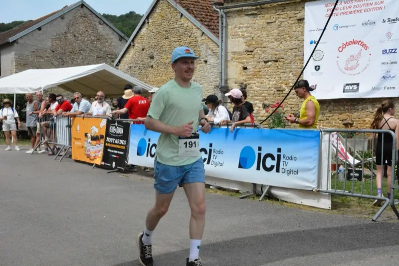 Un coureur termine la course devant les banderoles des partenaires