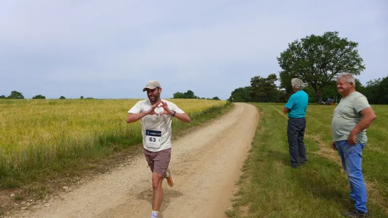 Un coureur fait un cœur avec les mains en passant devant les bénévoles du parcours
