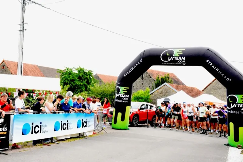 Les coureurs alignés sous l'arche de départ du Trail Côtelettes, encouragés par le public